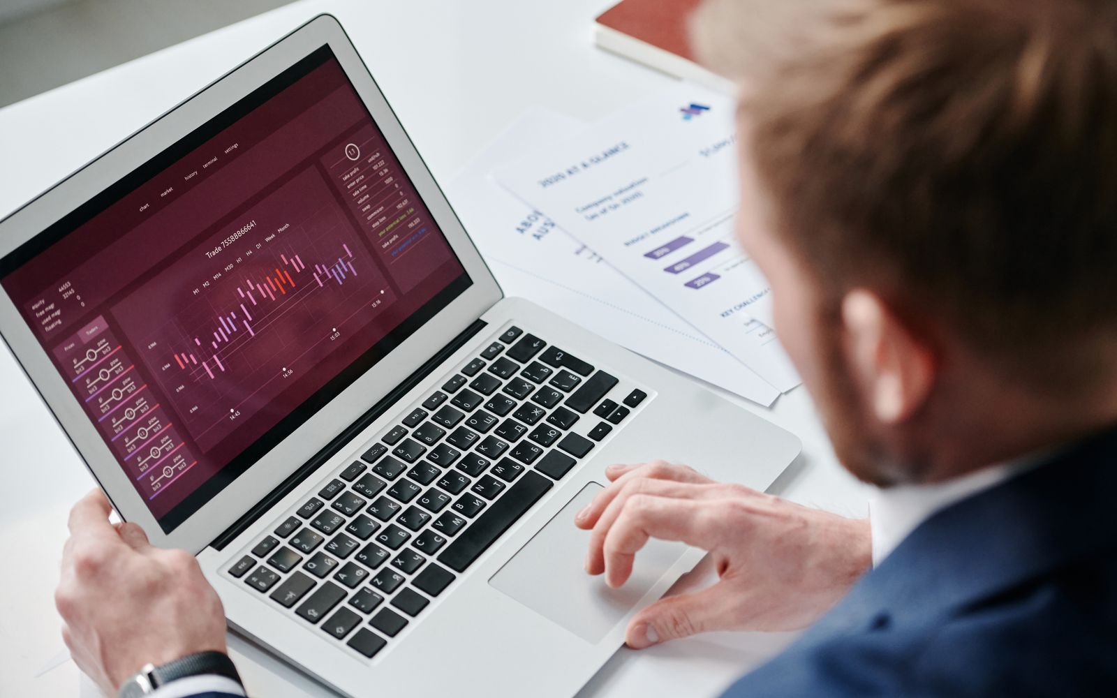 Businessman reviewing data analytics dashboard on laptop in bright office.
