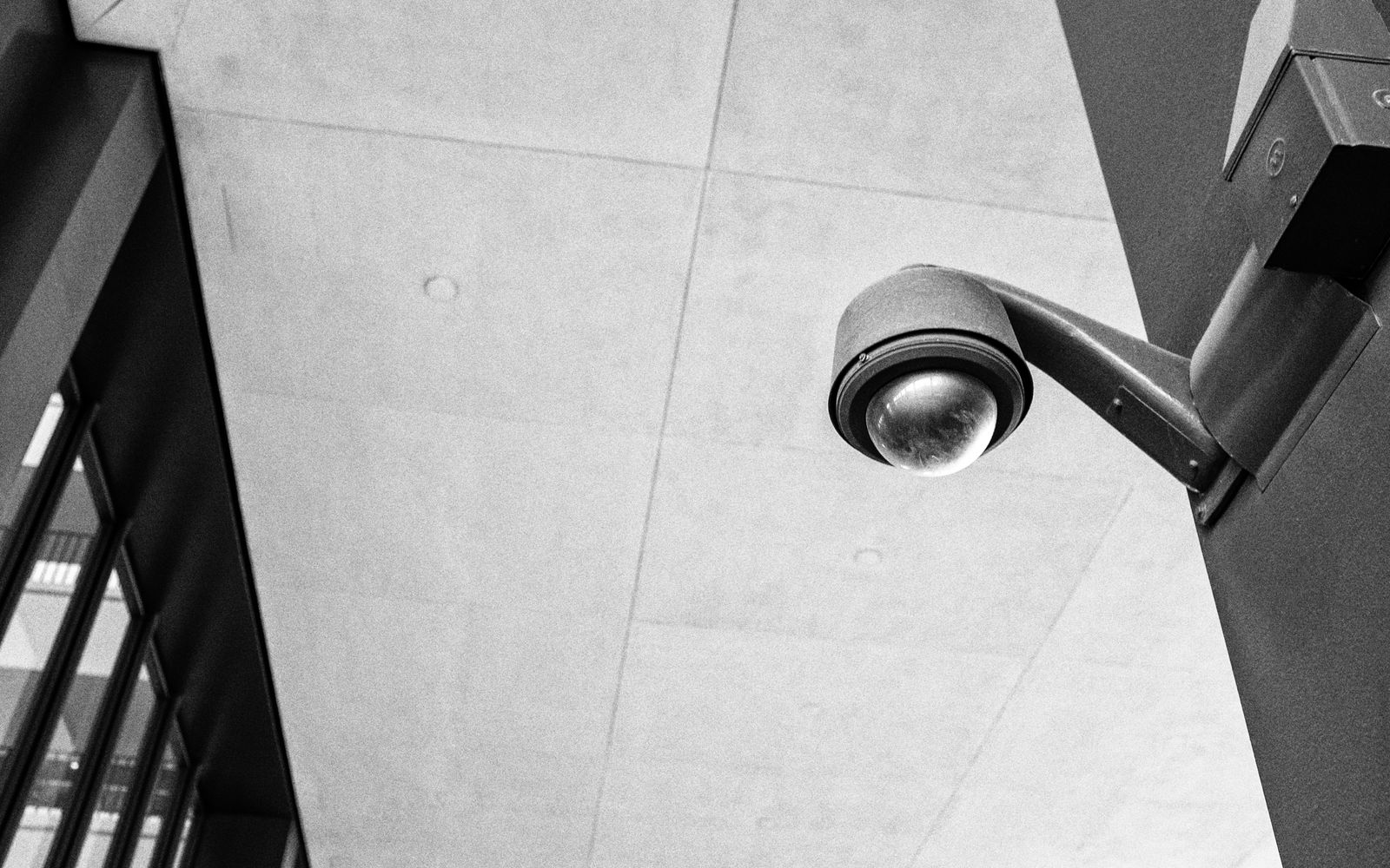 Monochrome image of a modern surveillance camera mounted outdoors, emphasizing security.