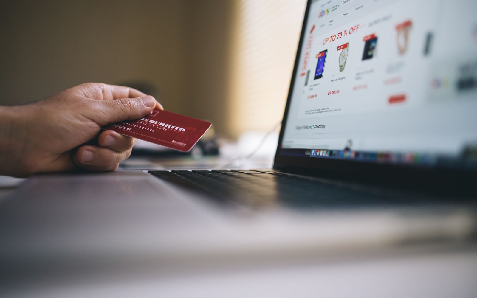 Person holding a credit card while shopping online on a laptop, indicating ecommerce transactions.