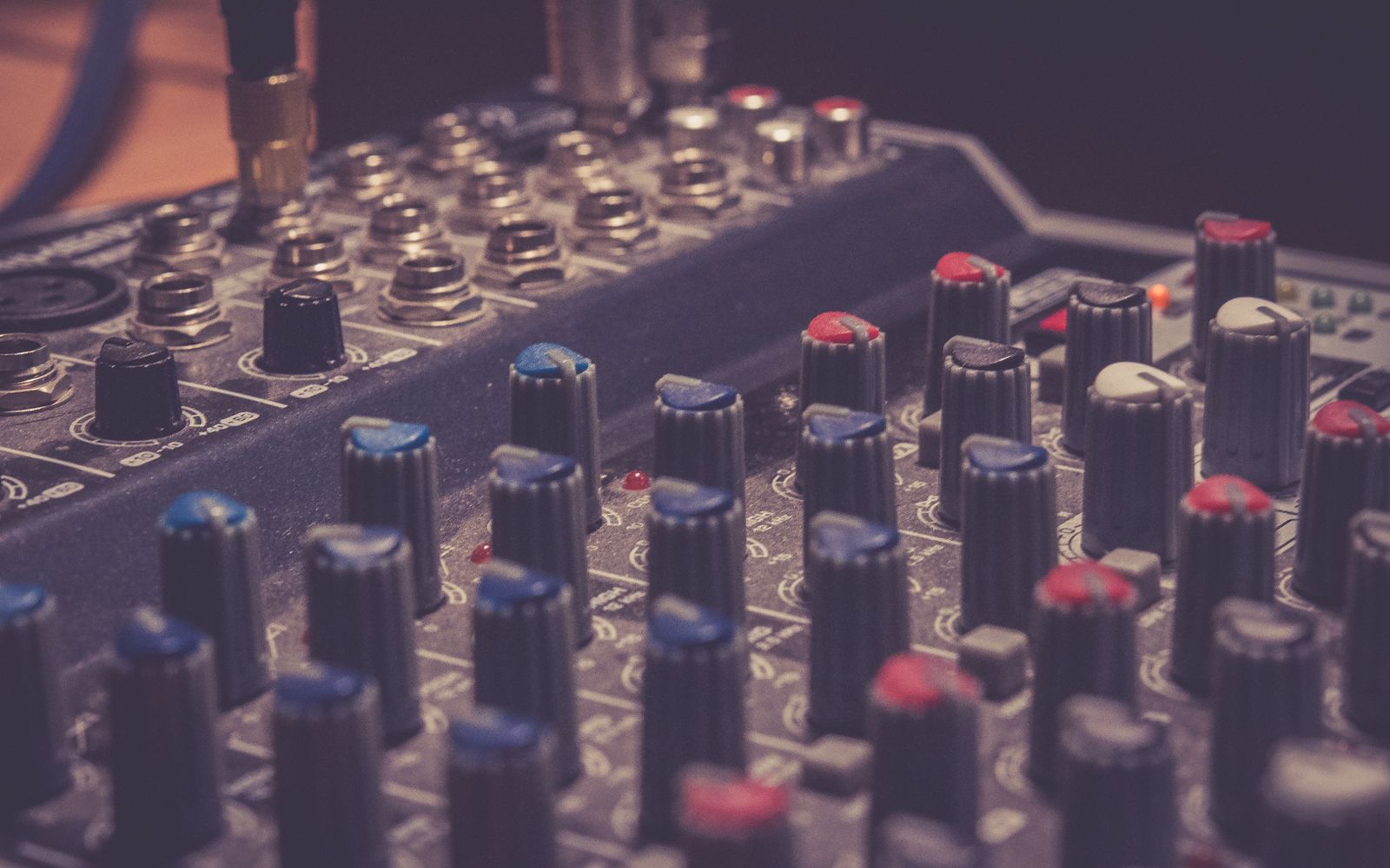 Detailed view of a professional audio mixer in a music studio, highlighting control knobs and switches.
