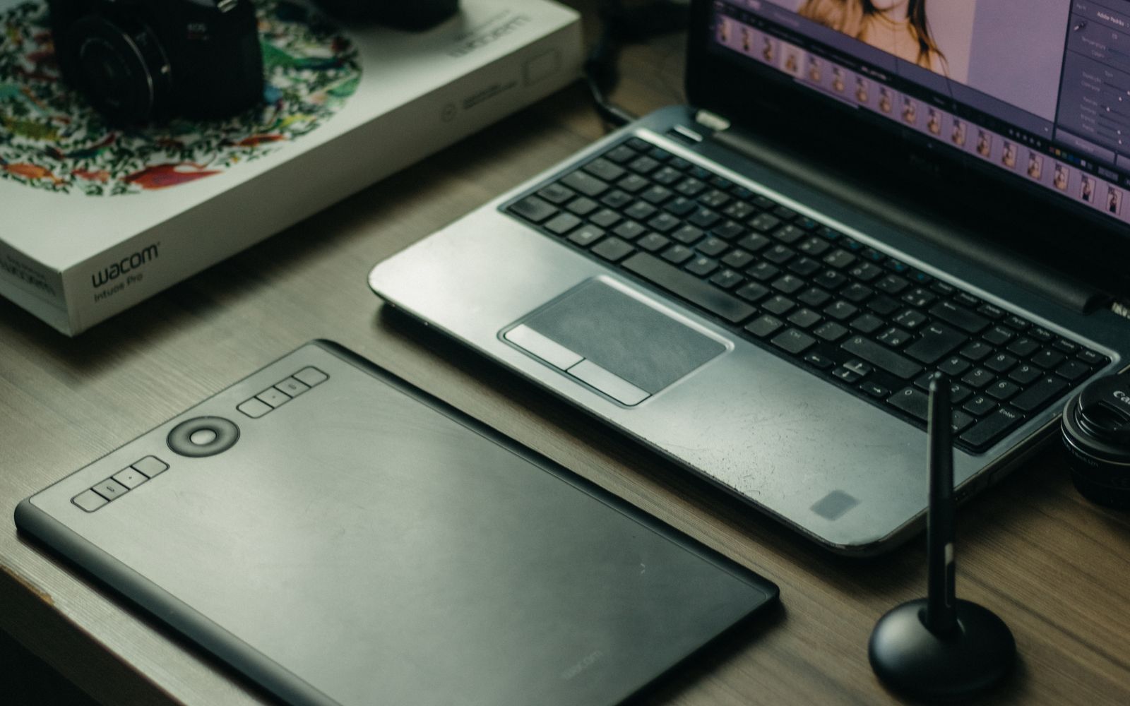 Modern digital artist setup with laptop, tablet, and stylus on desk.