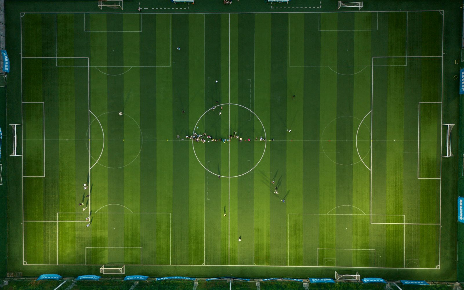 Top-down view of a soccer field with players during daytime.